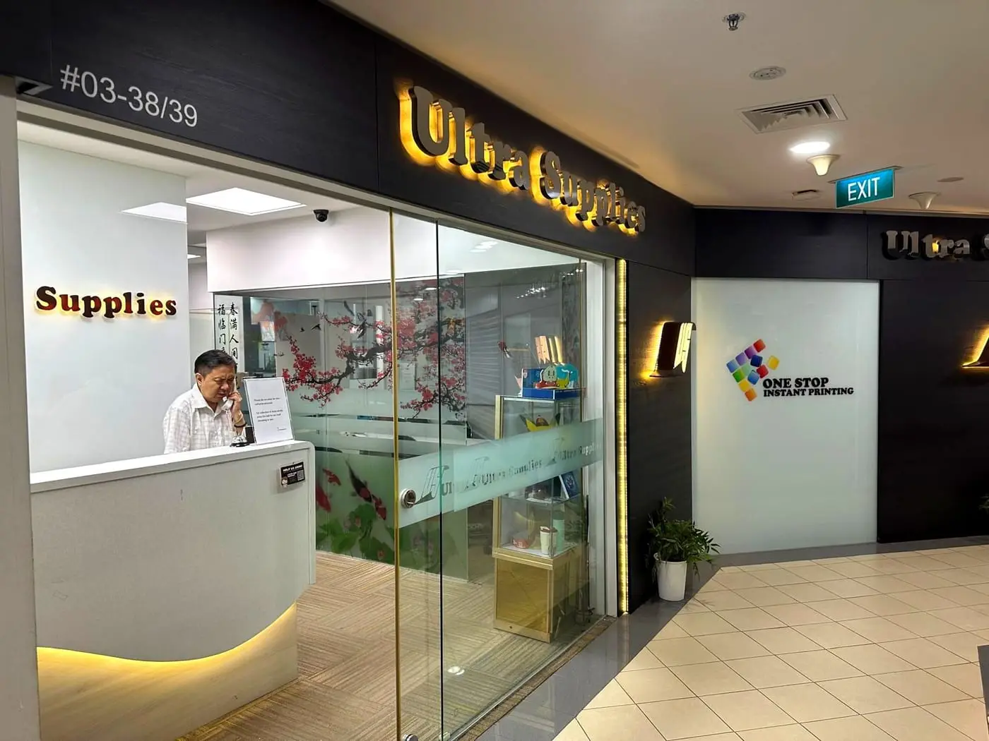 The Ultra Supplies shopfront at unit #03-38, with a gold "Ultra Supplies" sign above a glass door.